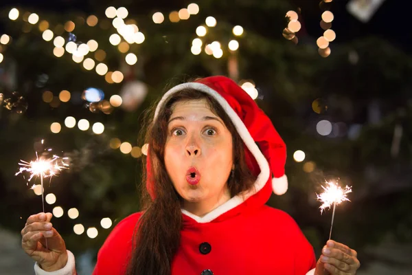 Menschen, Feiertage und Weihnachten - junge Frau im Weihnachtsmannkostüm mit Wunderkerzen oder Bengallicht — Stockfoto