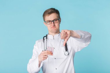 Başparmak aşağı hareketi ile beyaz tıbbi elbise erkek genç doktor