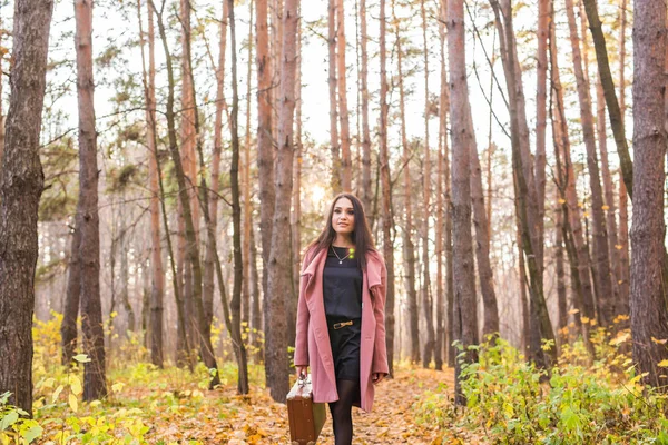 Seizoen, de natuur en de mensen concept - vrouw in herfst park poseren met koffer — Stockfoto