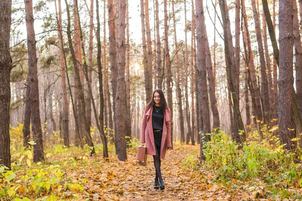 Осень, мода, люди концепция - женщина с коричневым ретро чемоданом прогуливаясь по осеннему парку и улыбаясь — стоковое фото