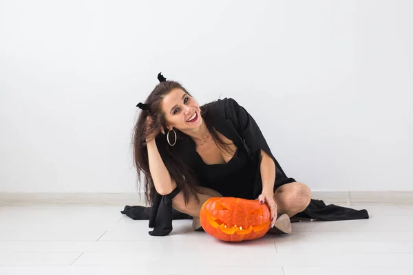 Gelukkig gotische jonge vrouw in heks halloween kostuum lachend over witte kamer achtergrond — Stockfoto