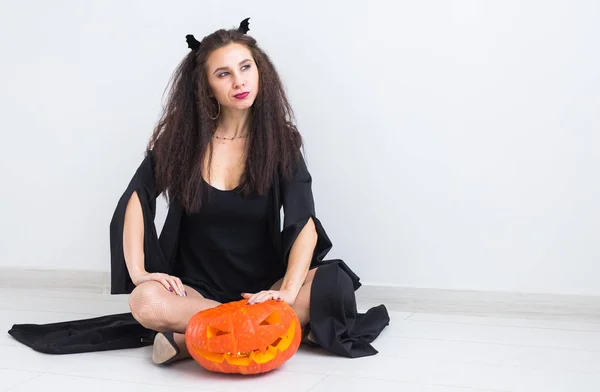 Femme gothique mignonne dans des vêtements de style halloween avec citrouille dans les mains — Photo