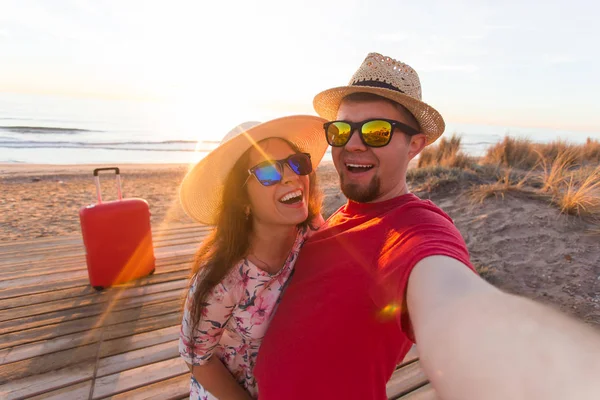 Viagens, férias e conceito de férias - Menina bonita e seu namorado bonito em chapéus de palha fazer selfie — Fotografia de Stock