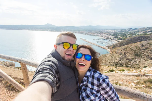 Koncepcja podróży, wakacji i wczasów - para piękny posiadające zabawy, biorąc selfie, szalony twarze emocjonalne i śmiejąc się. — Zdjęcie stockowe