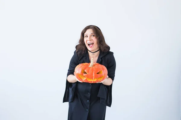 Excited happy young woman in halloween costume posing with carved pumpkin in lightroom — Stock Photo, Image