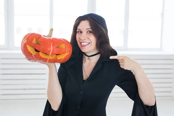 Niedliche gotische Frau in Halloween-Kleidung mit Kürbis in den Händen — Stockfoto