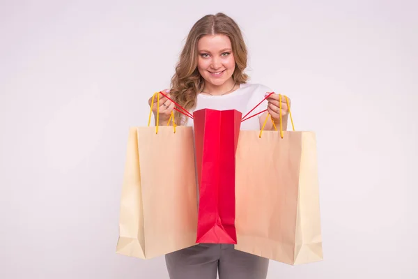 Feliz hermosa mujer caucásica mirando en bolsas de compras sobre fondo blanco — Foto de Stock