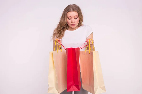 Joven mujer rubia sorprendida mirar en la bolsa de compras sobre fondo blanco — Foto de Stock