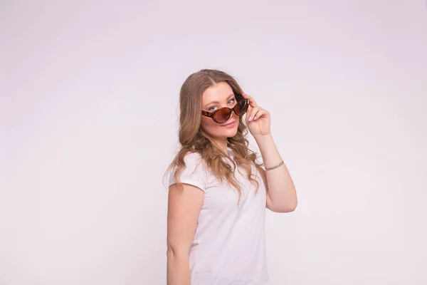 Güzel beyaz kıvırcık genç kadın kopya alanı ile beyaz arka plan üzerinde beyaz tişört ve güneş gözlüğü takıyor — Stok fotoğraf