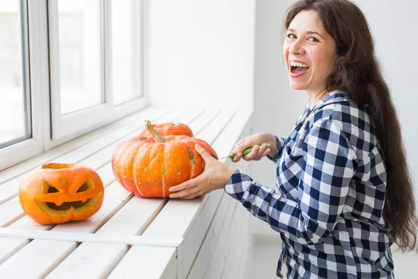 Holidays, halloween, decoration and people concept - close up of woman with pumpkins preparing to halloween
