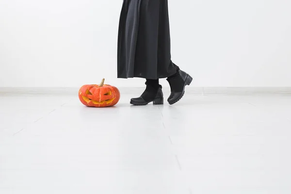 Gros plan de femme gothique dans des vêtements de style halloween avec citrouille sur fond clair avec espace de copie — Photo