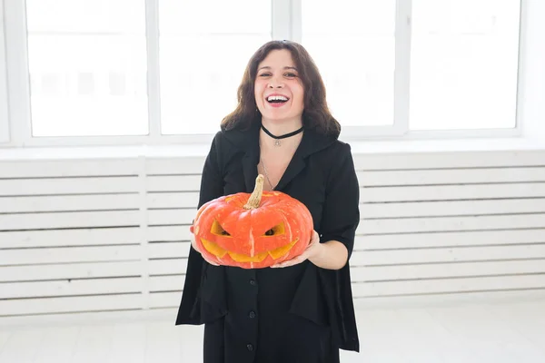 Femme gothique mignonne dans des vêtements de style halloween avec citrouille dans les mains — Photo