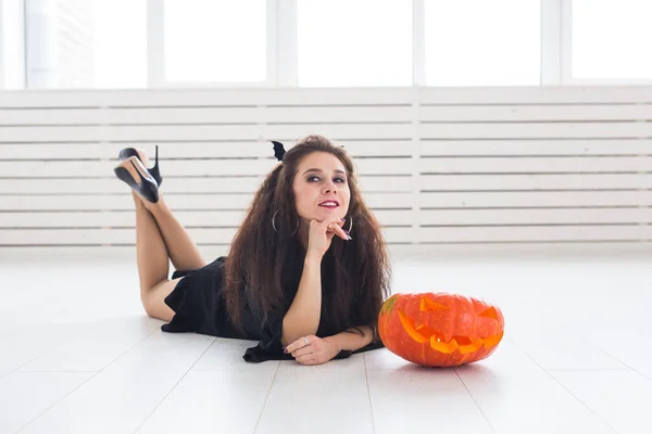 Retrato de una elegante morena con calabaza de halloween — Foto de Stock