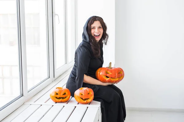 Excited happy young woman in halloween costume posing with carved pumpkin in lightroom — Stock Photo, Image