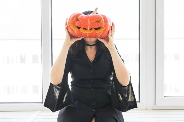 Gelukkig gotische jonge vrouw in heks halloween kostuum lachend over witte kamer achtergrond — Stockfoto