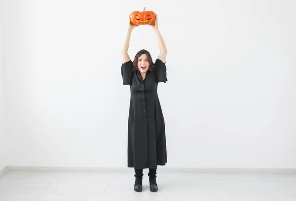 Halloween concept - Happy heks met hefboom-o-lantaarn van de pompoen op lichte achtergrond — Stockfoto