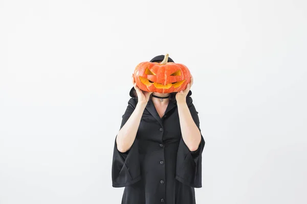 Halloween concept - anonieme heks met hefboom-o-lantaarn van de pompoen op lichte achtergrond — Stockfoto