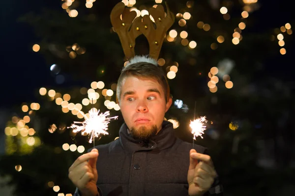 사람들, 휴일과 크리스마스 개념-deers 뿔 잡고 두 bengals 빛 또는 폭죽 야외에 놀된 사람 — 스톡 사진