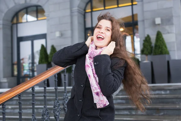 Emotions, city and people concept - laughing happy woman wearing scarf in winter street