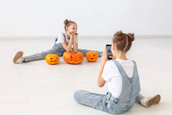 Bambini, gemelli e concetto di Halloween - Sorelle divertenti si fotografano a vicenda con lo smartphone — Foto Stock