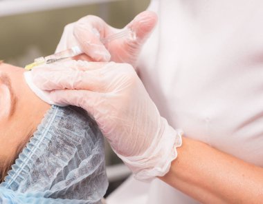 İnsanlar ve kozmetik kavramı - uzman Şevval özçelik güzellik kadın alnına botoks enjekte el yakın.