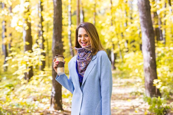 Sonbahar, Doğa, insanlar kavramı - mavi ceket daimi bir fincan kahve ile parkta genç esmer kadın