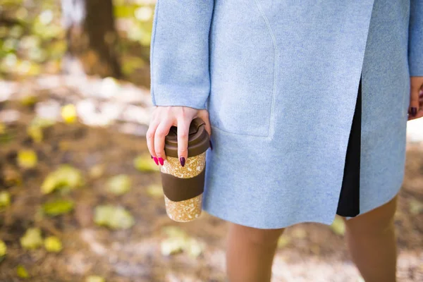 Primo piano della donna che tiene in mano una tazza di caffè da asporto sulla strada di autunno — Foto Stock