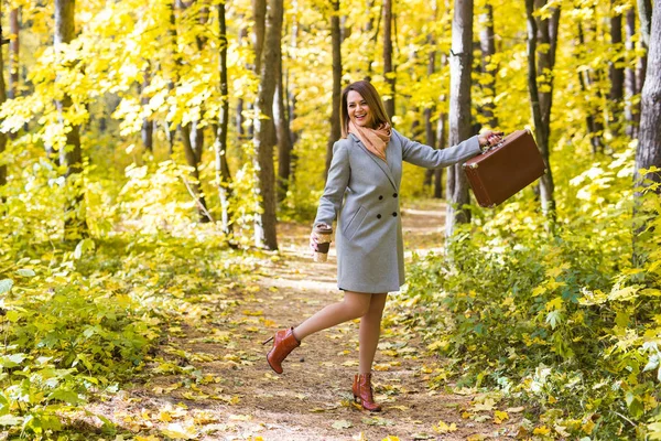 Outono, estação e conceito de pessoas - jovem mulher se divertir com mala retro no parque de outono — Fotografia de Stock