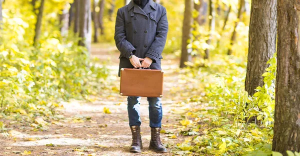 Conceito de queda, temporada e pessoas - Close-up de homem de pé com mala retro no parque no outono — Fotografia de Stock