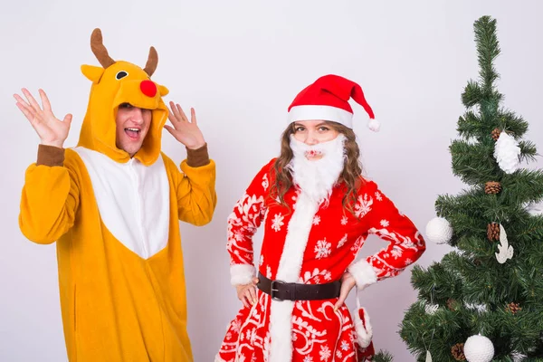 Concept amusant, Noël et vacances - femme heureuse en costume de Père Noël avec l'homme en costume de cerf va vous féliciter avec joyeux Noël — Photo