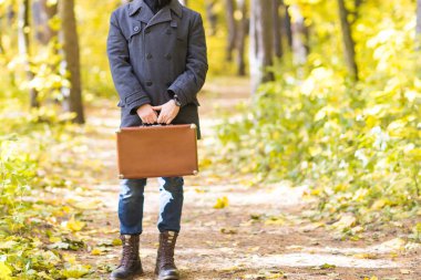 Sonbahar, mevsim ve insanlar kavramı - Park retro çanta sonbahar duran adamın yakın