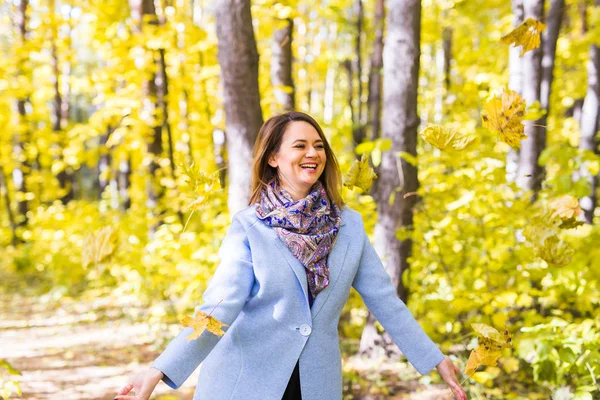 Herfst, natuur en leuk concept - mooie jongedame in blauwe vacht gooien boeket van bladeren — Stockfoto