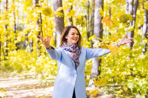 Herfst, vreugde en mensen concept - jonge vrouw plezier in herfst park. Ze is het gooien van gele bladeren in een hemel — Stockfoto