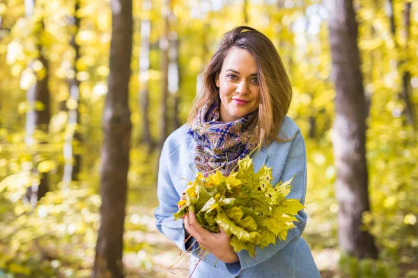 Automne, nature et peuple concept - Jeune belle femme en manteau gris tenant bouquet de feuilles d'automne — Photo