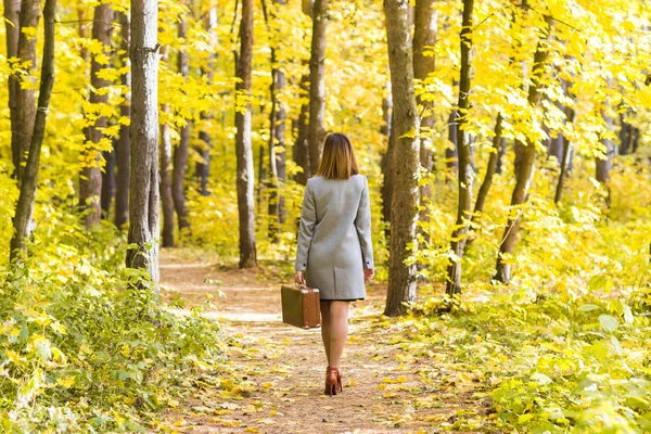 Zobacz stylowe, młodej kobiety z powrotem z walizki retro spacer w parku jesień — Zdjęcie stockowe