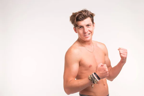 Люди, жест и спортивная концепция - молодой уверенный в себе мужчина без рубашки показывает кулаки на белом фоне с копировальным пространством — стоковое фото