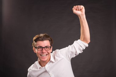 Kazanan jest koyu arka plan üzerinde gösterilen beyaz tişörtlü yakışıklı adam