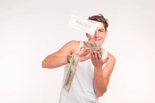 Bohaté, fun a finance koncept - pohledný mladý muž hází peníze nad bílým pozadím. — Stock fotografie