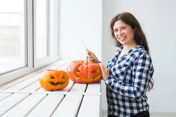 Holidays, halloween, decoration and people concept - close up of woman with pumpkins preparing to halloween