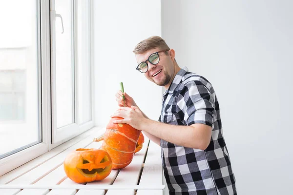 Holidays, halloween, decoration and people concept - close up of man with pumpkins preparing to halloween