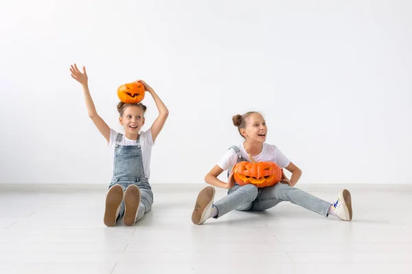 Хэллоуин, дети и веселая концепция - Счастливые веселые сестры близнецы стоя с Jack-о-фонарь на голове на белом фоне — стоковое фото