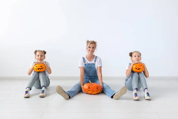 Aile, sonbahar ve tatil kavramı - anne ve Jack-O-Lantern kabak Cadılar Bayramı günü tutarak onun kızı ikiz. — Stok fotoğraf