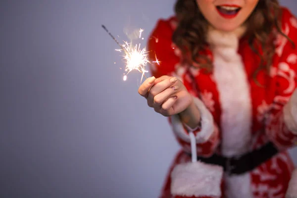 Gros plan de santa claus femme en rouge Noël ou Nouvel An manteau et chapeau tenant scintillant et feu de bengale sur fond avec espace de copie — Photo