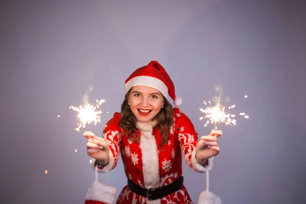 Jeune femme santa claus en rouge Noël ou Nouvel An manteau et chapeau tenant feu scintillant et bengale . — Photo