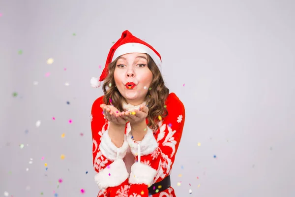 İnsanlar, Noel ve tatil kavramı - Noel Baba'ya oldukça genç bayan beyaz arka plan üzerinde üfleme konfeti kostüm — Stok fotoğraf