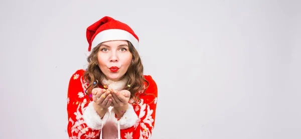 Tatil, Noel ve insanlar kavramı - Noel Baba kostüm konfeti üzerinde üfleme kopya alanı ile beyaz arka plan üzerinde güzel ve genç kadın — Stok fotoğraf