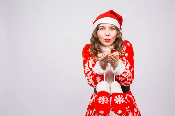 İnsanlar, Noel ve tatil kavramı - Noel Baba kostüm kopya alanı beyaz zemin üzerine konfeti üfleme oldukça genç bayan — Stok fotoğraf