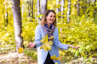 Sonbahar, sevinç ve insanlar kavramı - genç kadın sonbahar parkta eğleniyor. O bir gökyüzünde sarı yapraklar atıyor