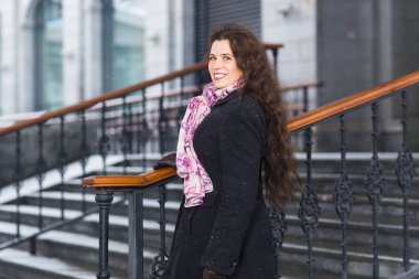 İnsanlar, moda ve kış konsepti - genç kadın merdiven arka plan üzerinde paltoyla poz