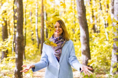 Sonbahar, sevinç ve insanlar kavramı - genç kadın sonbahar parkta eğleniyor. O bir gökyüzünde sarı yapraklar atıyor